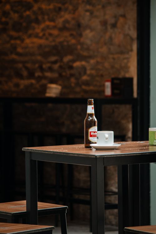 Free A tranquil bar scene featuring a bottle of beer and a coffee cup on a table. Stock Photo