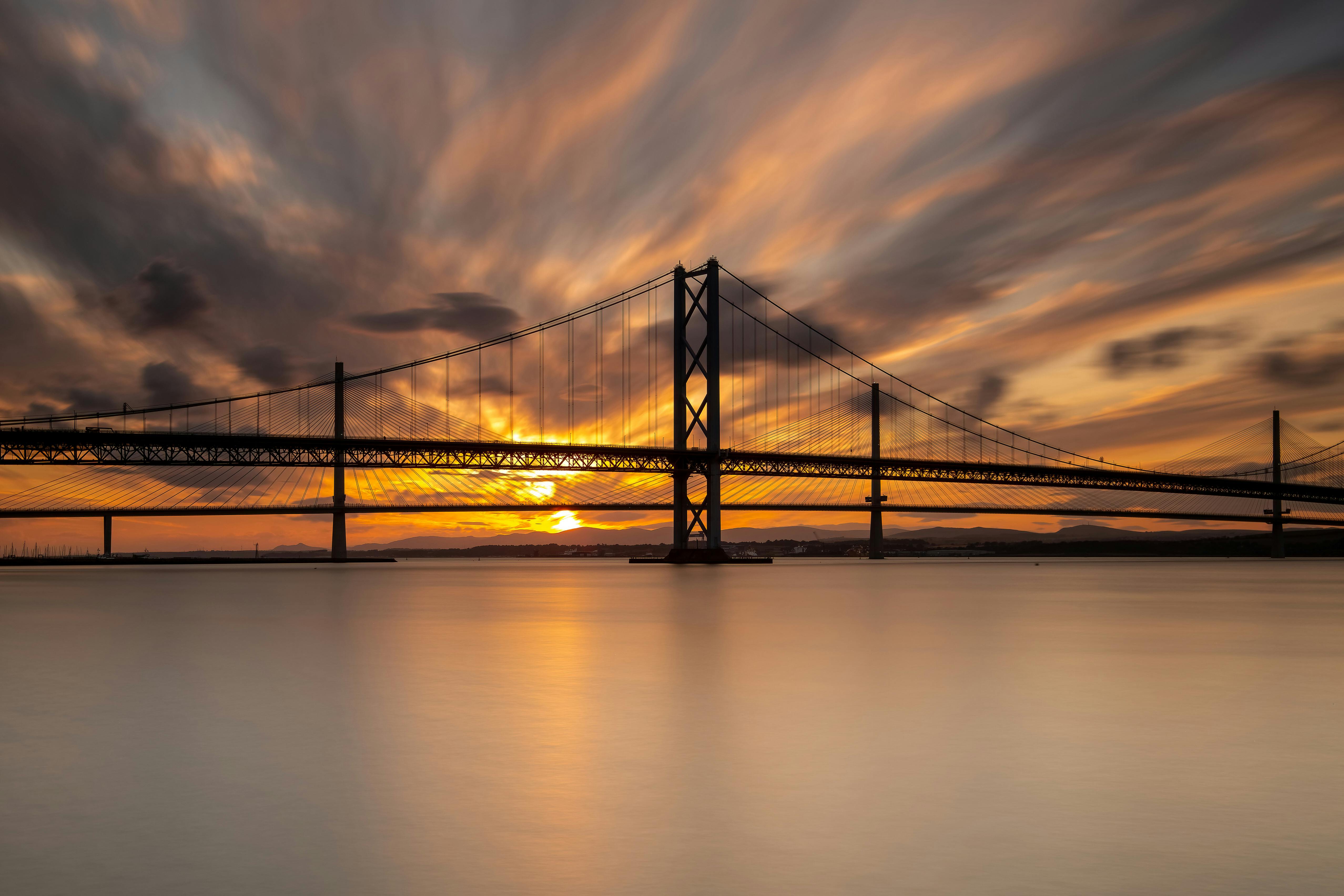 Stunning sunset over Forth Road Bridge with dramatic sky reflections.