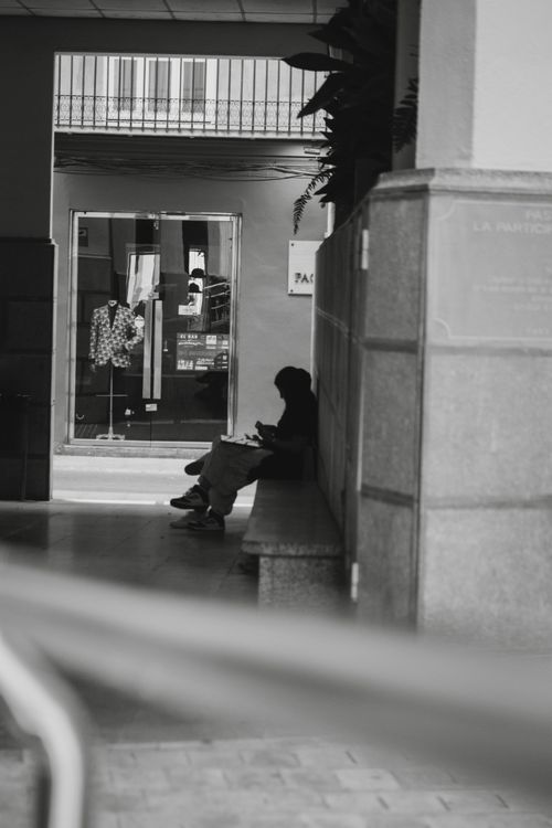 Free A solitary figure sits on a bench in an urban tunnel, captured in monochrome. Stock Photo