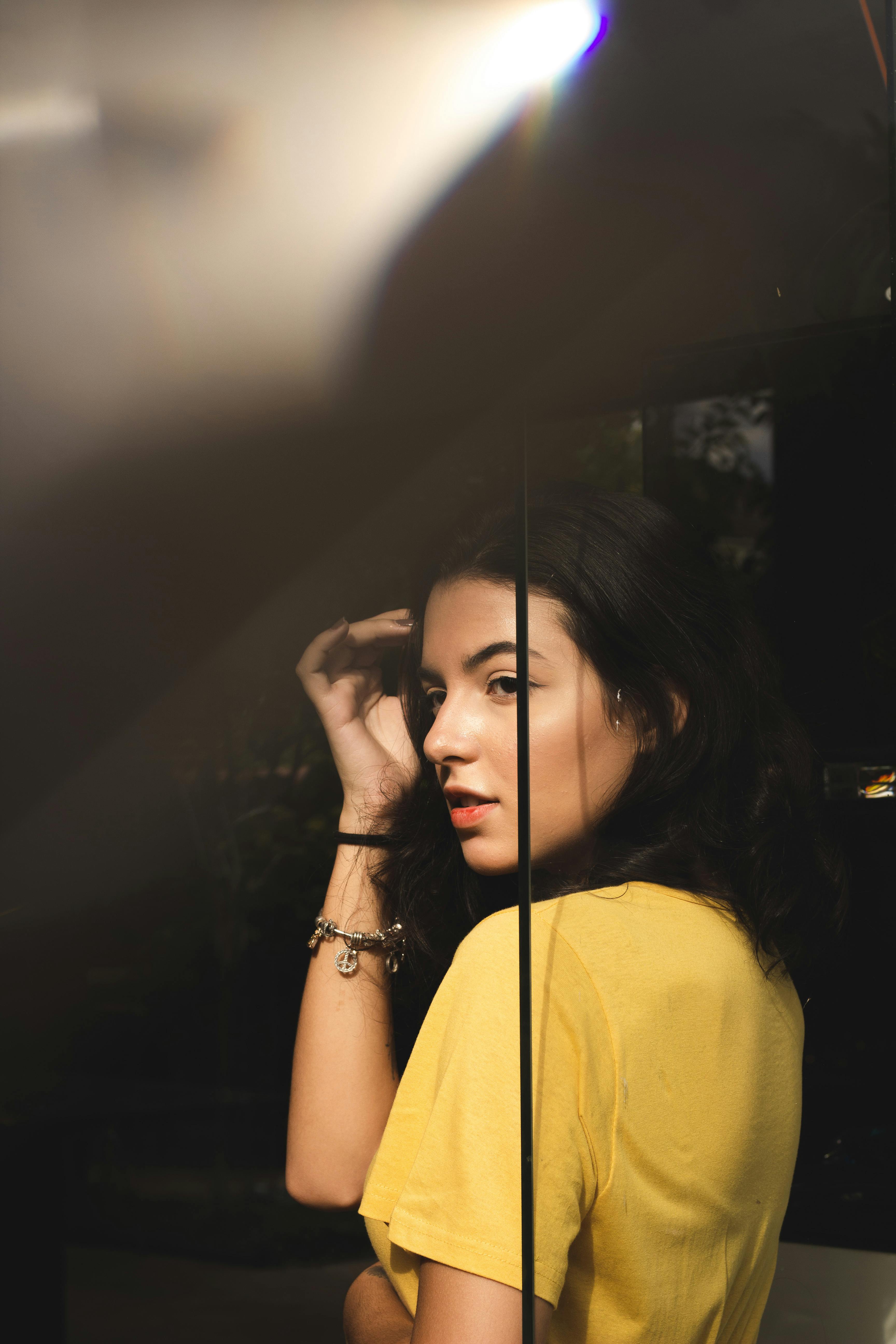 一位身着黄色衬衫的优雅女性肖像，光影效果美丽而富有戏剧性