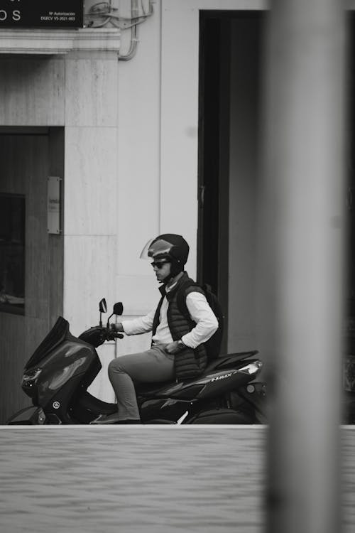 Black and White Photo of a Man on a Motor Scooter 