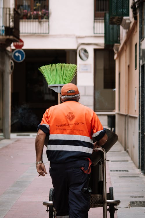 Cleaning Worker Pushing a Cart with a Broom on a City Street