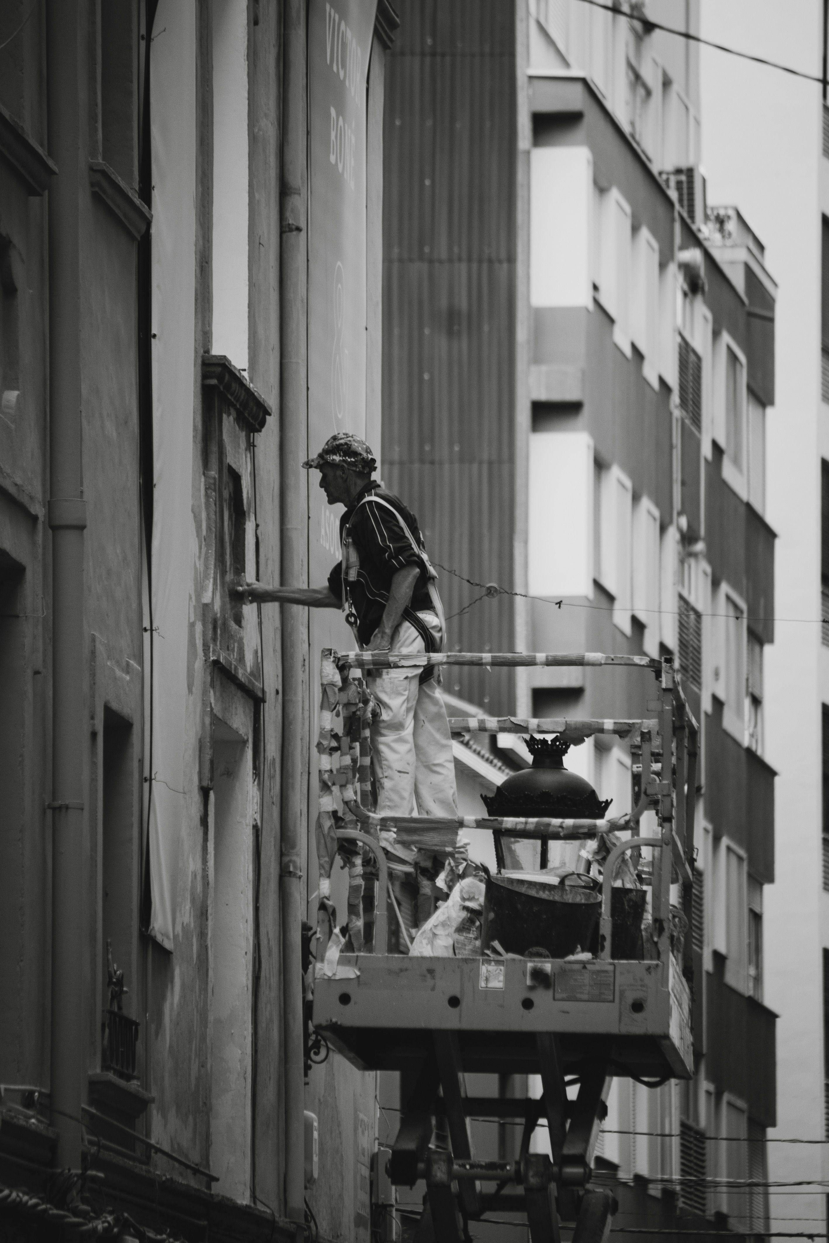 Man Repairing a Building Wall Standing on Hydraulic Platform · Free ...