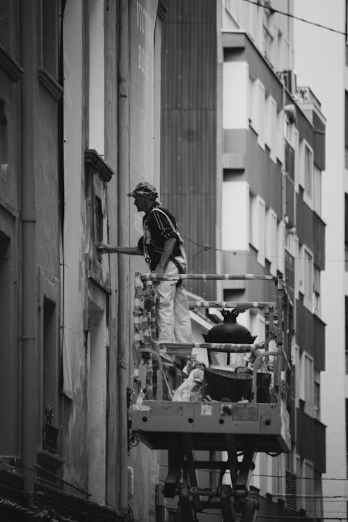 Man Repairing a Building Wall Standing on Hydraulic Platform