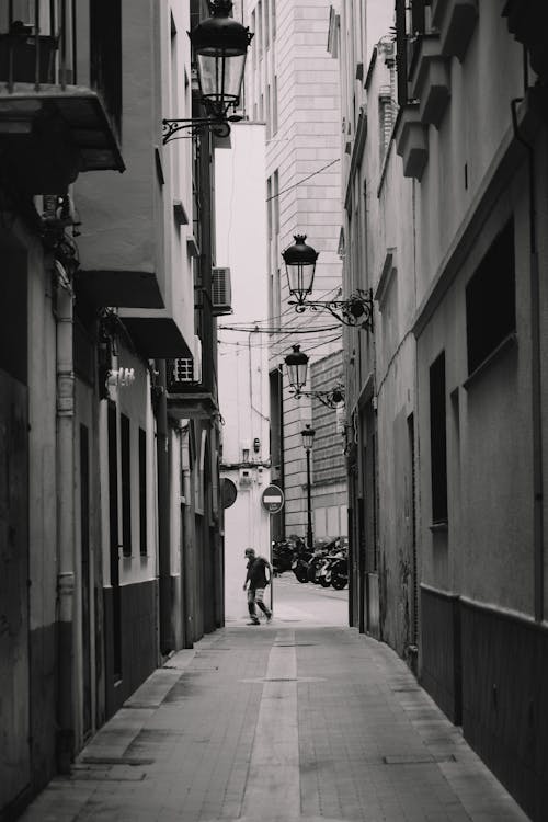 Black and White Photo of a Narrow Street between Buildings in City 