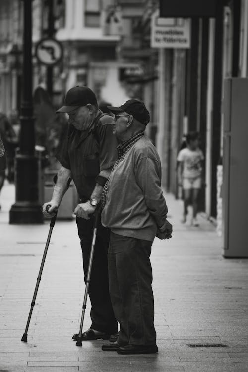 Black and White Photo of Two Senior Men Standing on a Street
