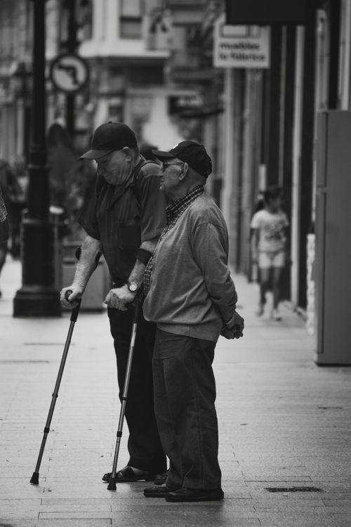 Free Two senior men with canes conversing on a city street in black and white. Stock Photo