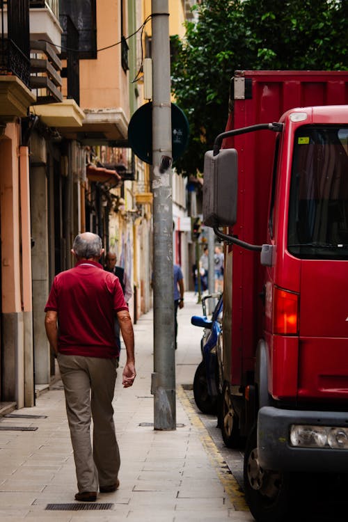 Elderly Man in Red T-Shirt Walking Down Street