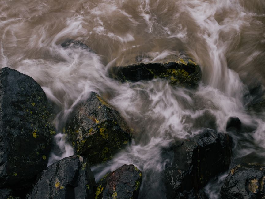 A captivating image of water flowing over dark, mossy rocks, capturing the motion and texture of the scene.