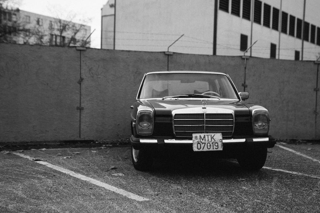 Black Vehicle Parked Near Concrete Wall in Grayscale Photography