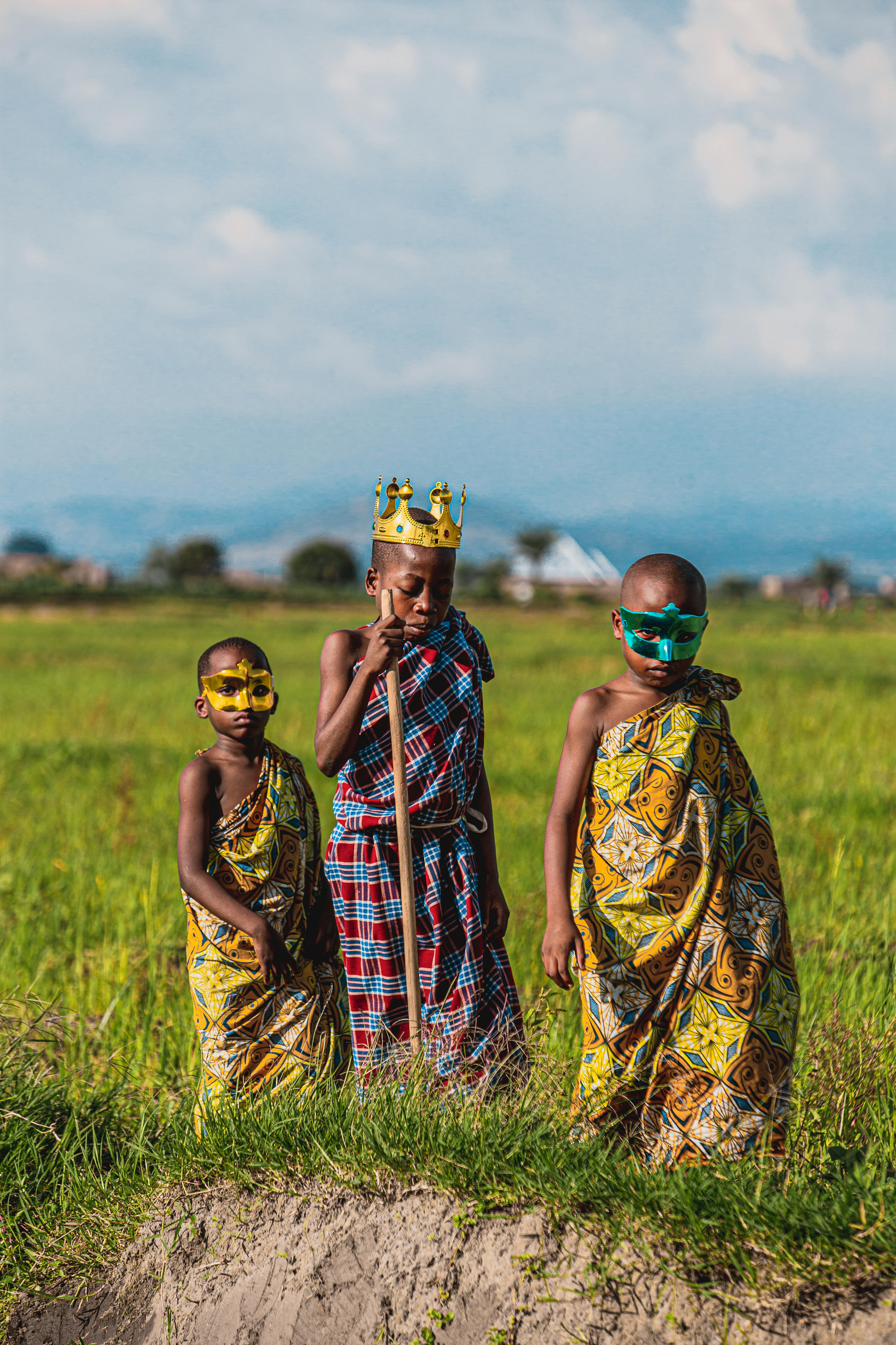 boys in traditional clothing and crown and masks on field