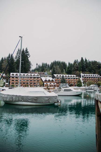 Serene harbor with docked yachts and hotel buildings among lush greenery.