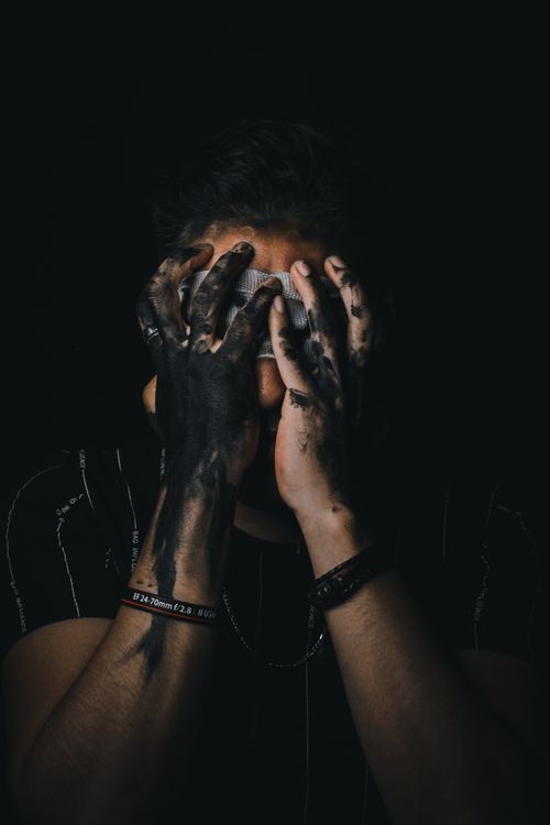 Free Dark portrait of man covering face with dirty hands, creating a mysterious atmosphere. Stock Photo