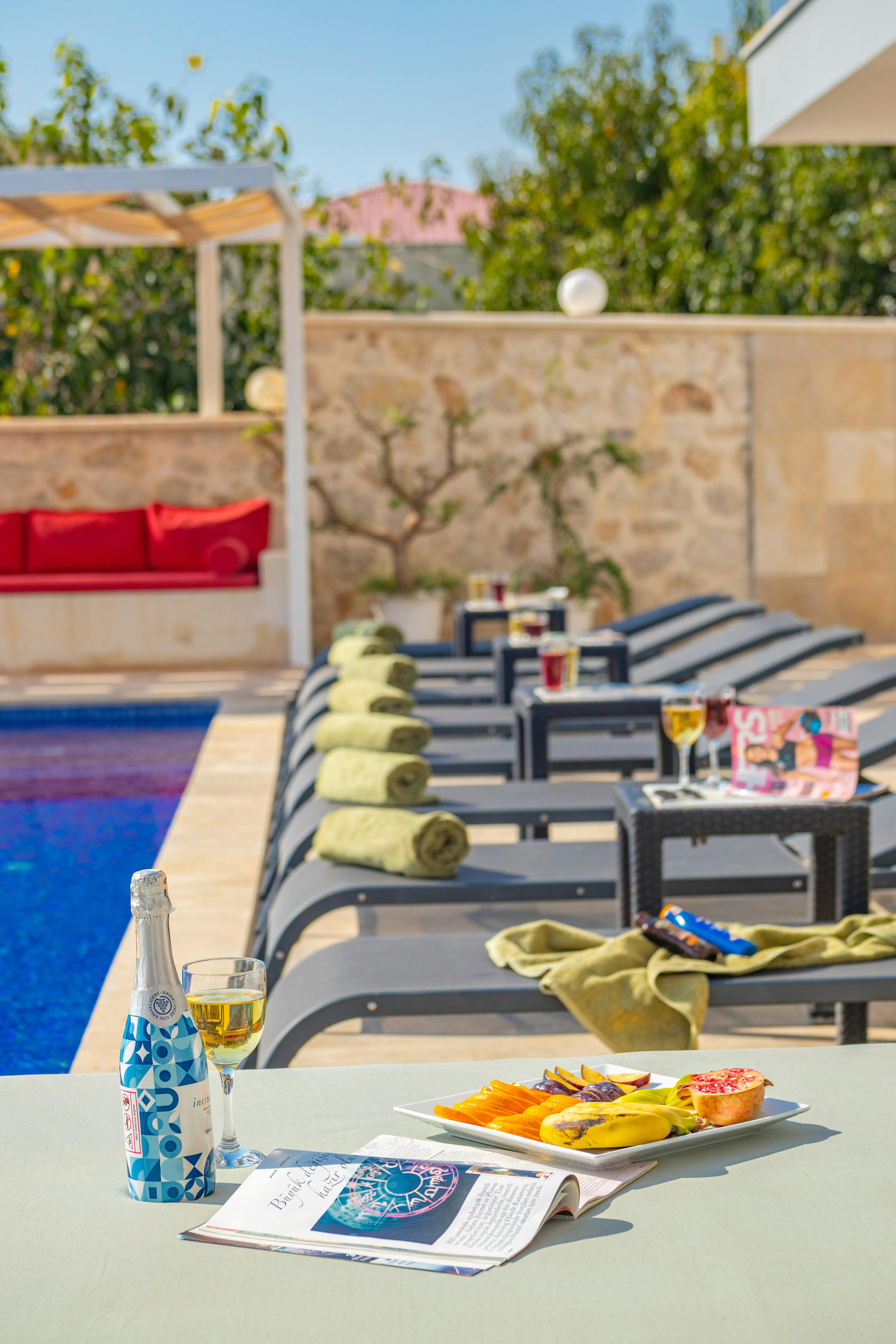 Free Relaxing poolside setting with snacks, drinks, and sun loungers under summer sunlight. Stock Photo