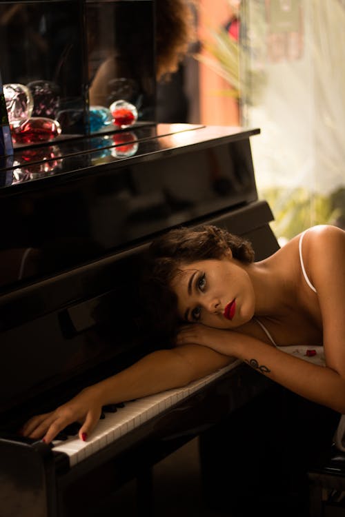 Woman Lying on Brown Wooden Piano
