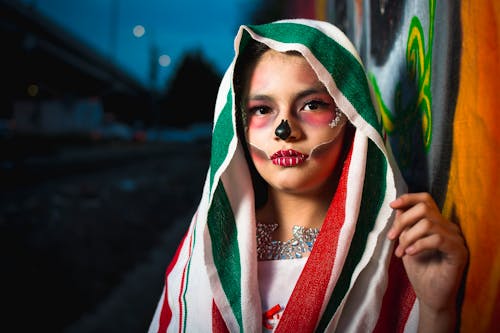 Young Woman Dressed as a Catrina Standing by the Wall in the Evening 