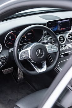 Close-up shot of a Mercedes Benz car dashboard and steering wheel featuring sleek design and modern technology.