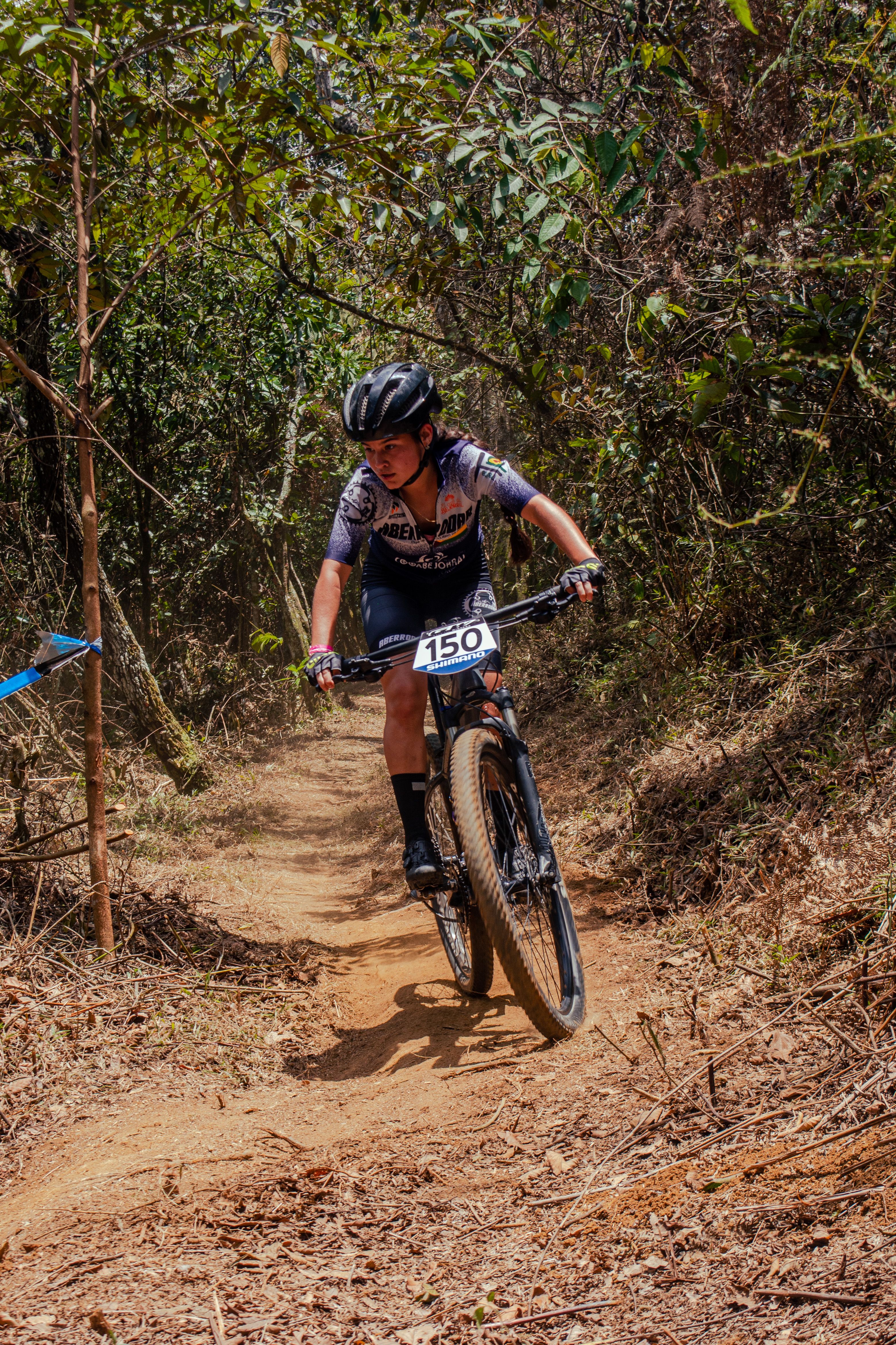 Teenager racing on a mountain bike through a forest trail, illustrating athleticism.