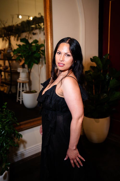 Woman in a Black Dress Standing in a Room with a Mirror 