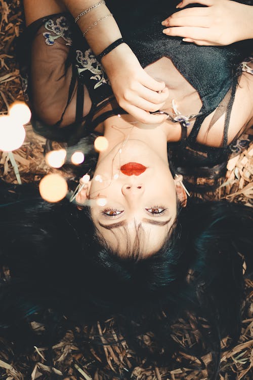 Woman Wearing Black Dress Lying on Dry Grass