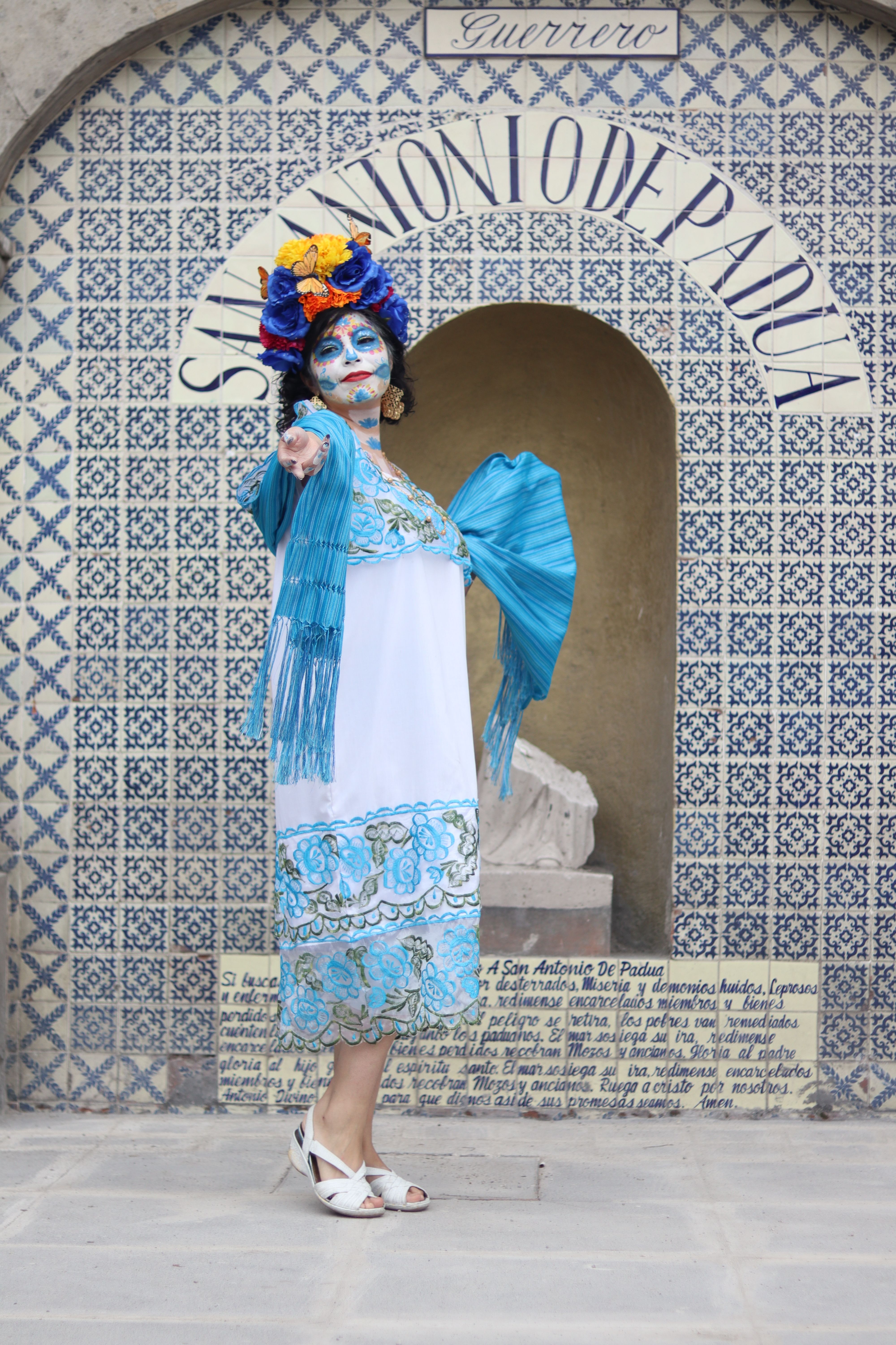 Colorful traditional attire with makeup at San Antonio de Padua backdrop, celebrating local culture.