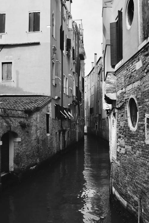 Black and White Photo of a Narrow Canal between Houses in Venice, Italy 