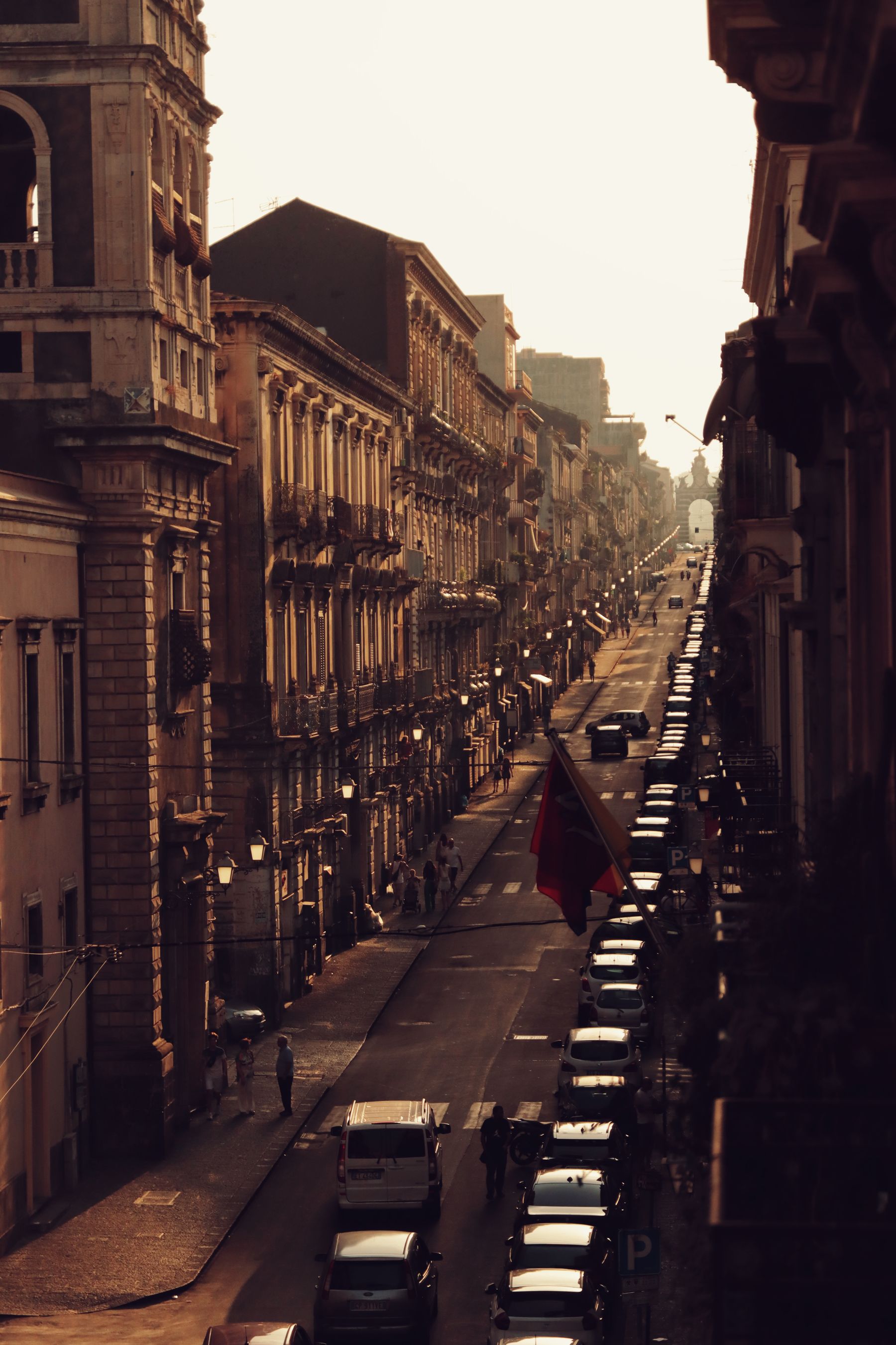 A long street of brownstone buildings in warm evening light