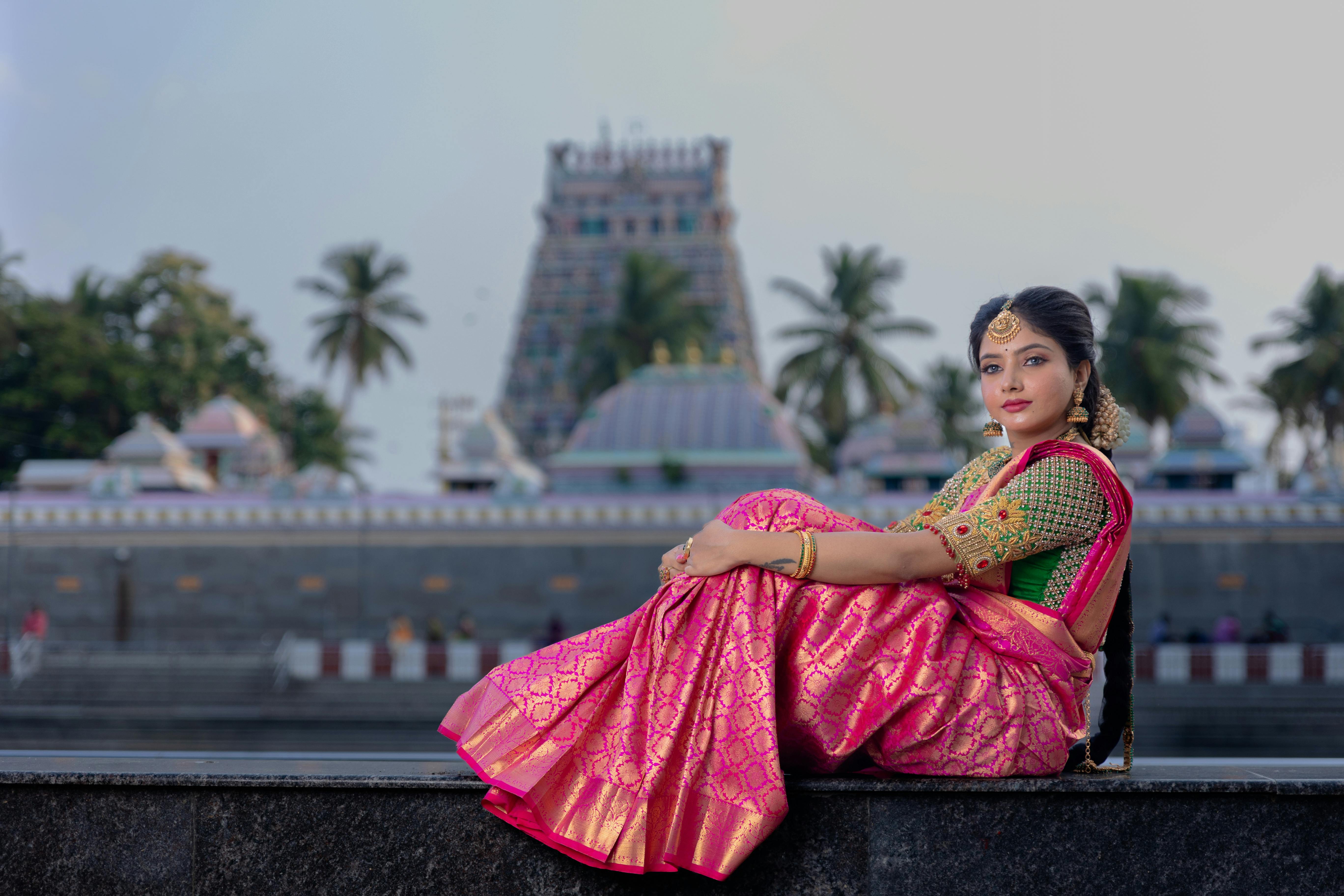 free photo of young woman in a traditional pink saree dress posing outside