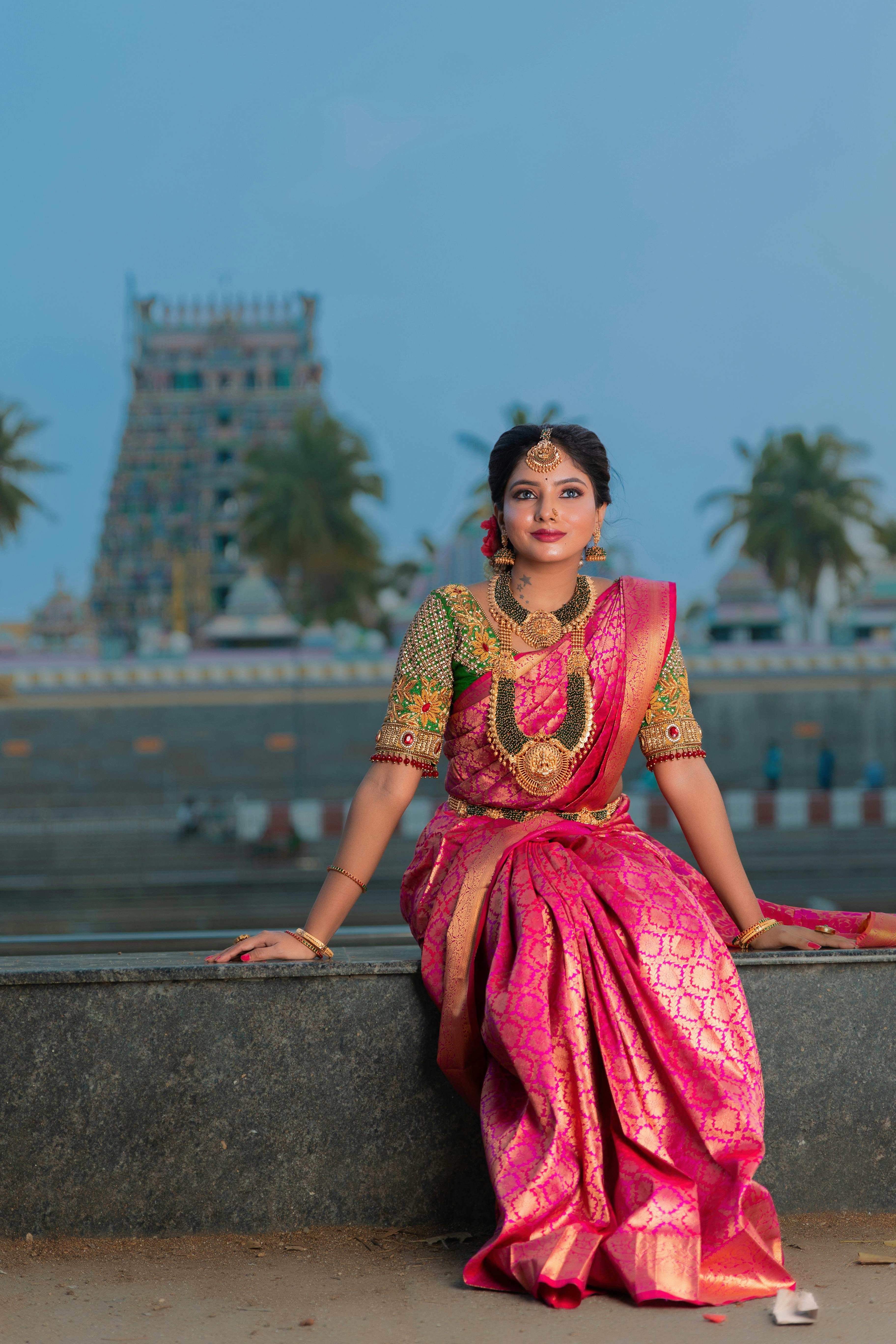free photo of young woman in a traditional pink saree dress posing outside
