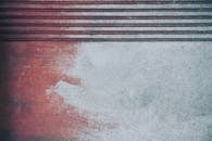 特写视图展示了带有红色色调和平行线纹理的染色混凝土表面