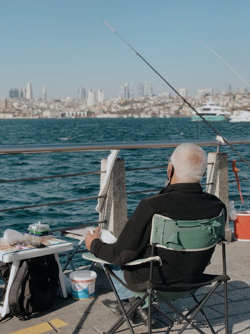 Back View of a Man Sitting on a Pier and Fishing 