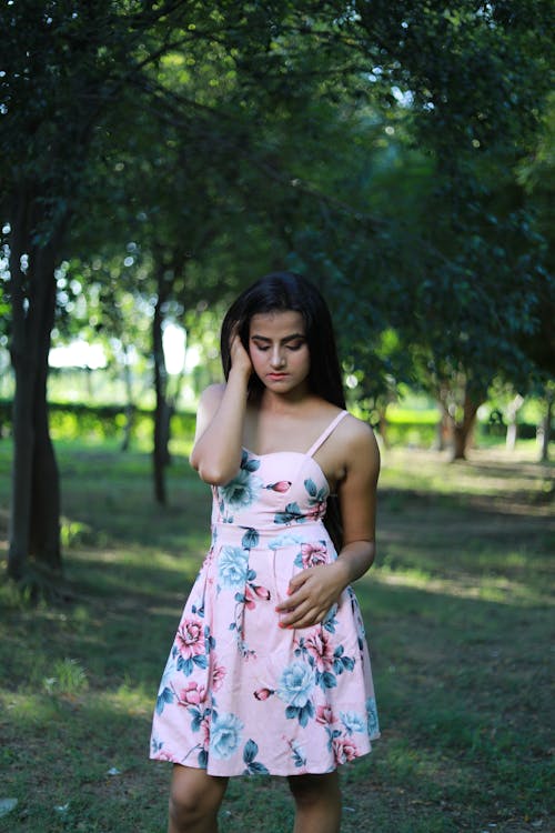 Young Woman in a Dress Standing in a Park 