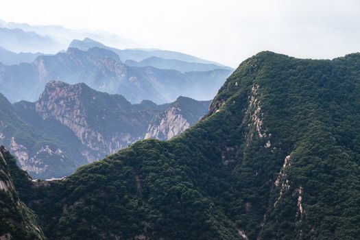 A stunning aerial view capturing the lush green mountains and distant misty peaks, showcasing natural beauty.