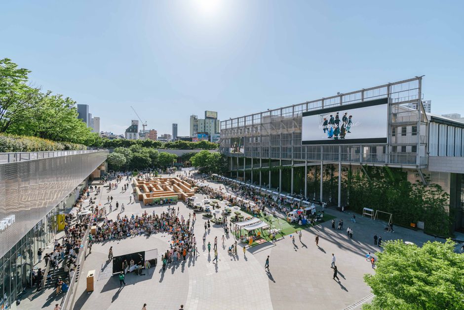 晴れた日に現代的な都市広場で楽しむ人々で賑わう屋外市場。ライフスタイルや旅行コンテンツに最適です。