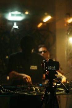 Dynamic DJ set in a nightclub captured with a camera on a tripod, featuring moody lighting.