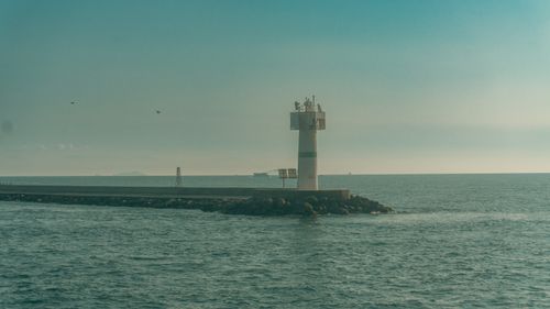Free Serene lighthouse on a breakwater with a calm ocean backdrop, conveying safety and navigation. Stock Photo