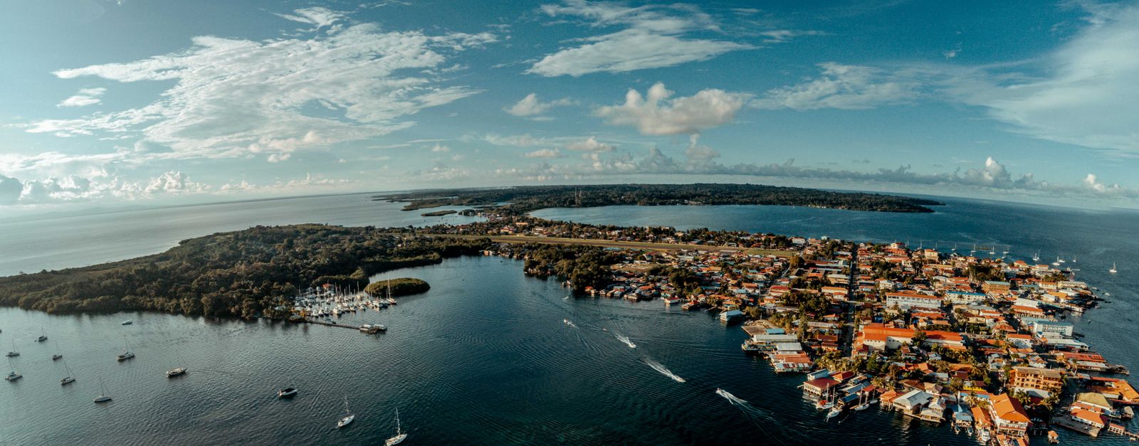 Stunning aerial view of a coastal town with marinas and yachts in a tropical island setting.