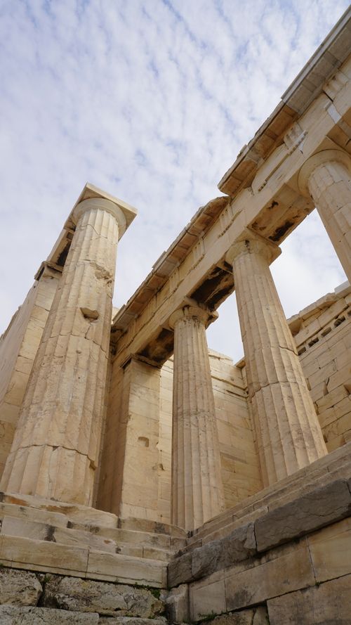 Free Low angle view of the Parthenon's ancient columns in Athens, Greece, against a cloudy sky. Stock Photo