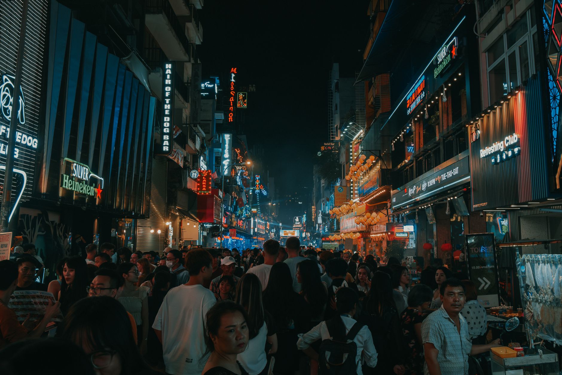 Experience the vibrant nightlife on a bustling city street filled with people, lights, and energy.