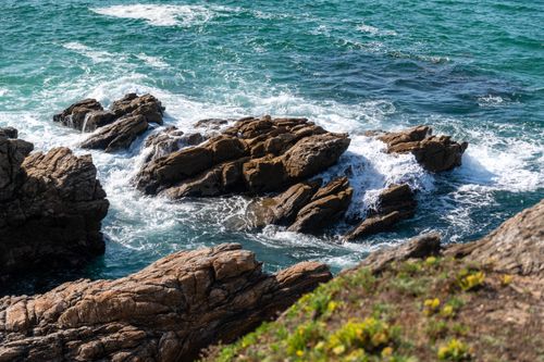 Free Stunning view of a rocky coastline with ocean waves crashing onto the shore under a bright sky. Stock Photo