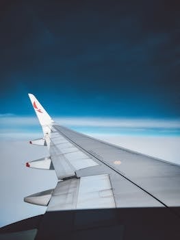 A serene view from an airplane window showcasing the wing against a gradient blue sky.