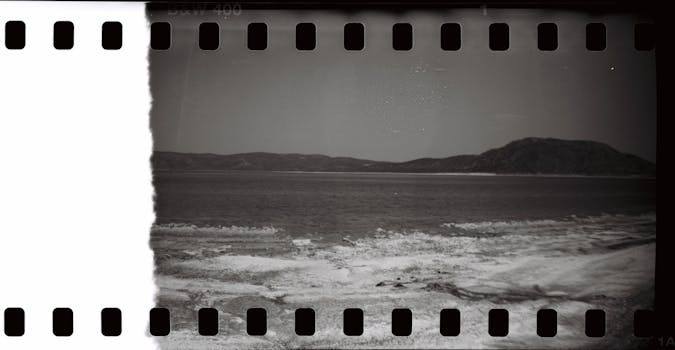 A nostalgic black and white photo of a serene seaside with distant hills.
