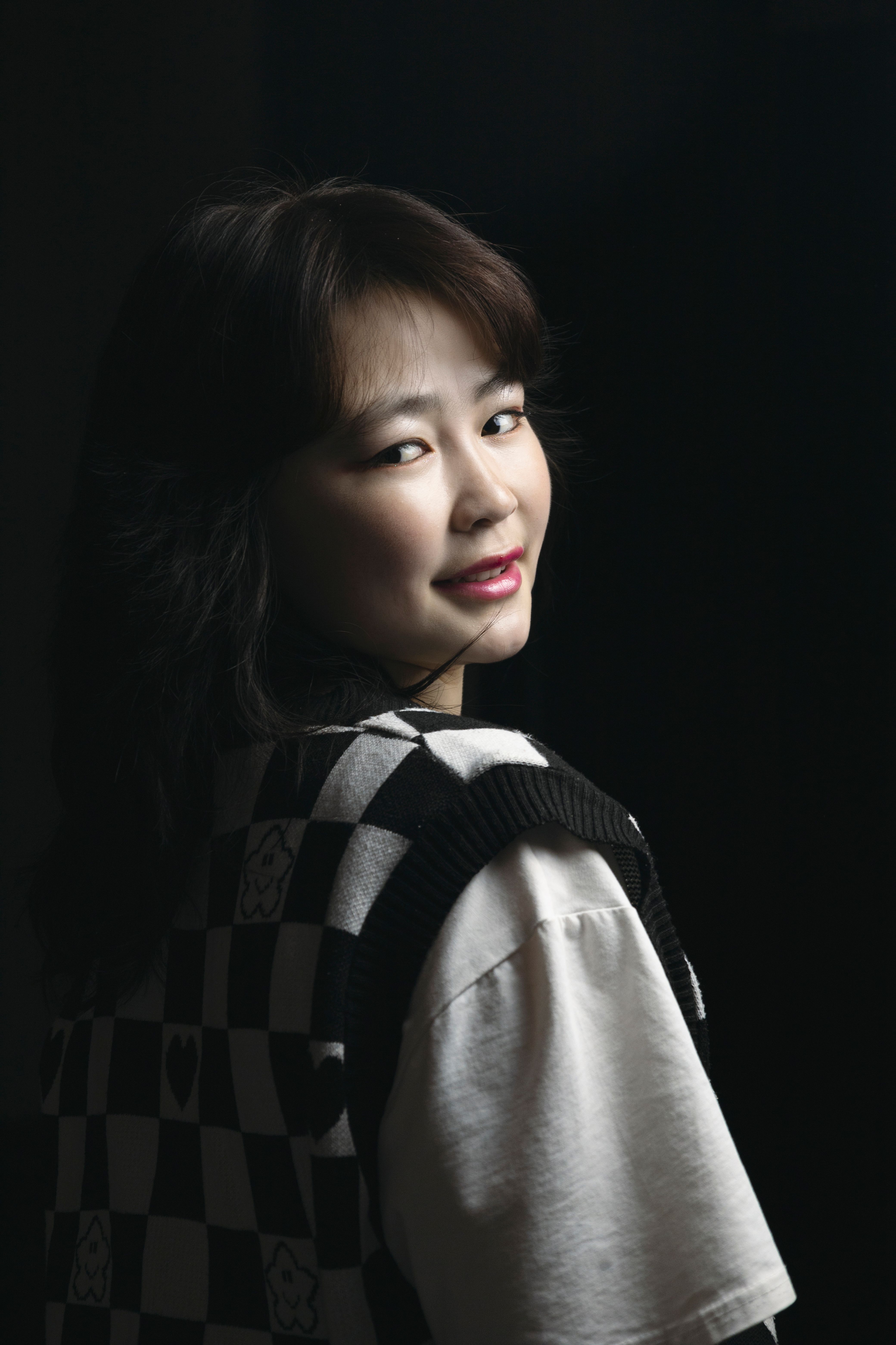 Studio portrait of a young woman in dark lighting, showcasing a classic and moody style.