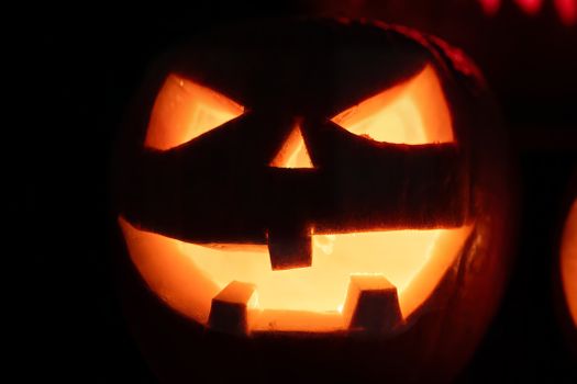 Close-up of a glowing jack-o'-lantern with a scary expression, perfect for Halloween.