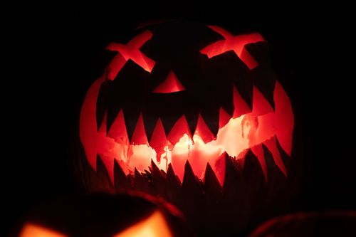 Free Close-up of a lit jack o' lantern with a scary face, perfect for Halloween themes. Stock Photo