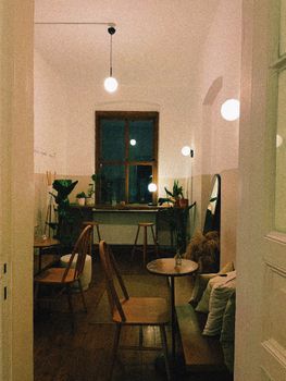 A cozy café featuring wooden furniture, plants, and ambient lighting, creating a warm atmosphere.