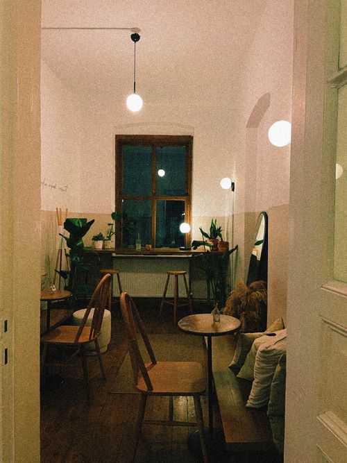Free A cozy café featuring wooden furniture, plants, and ambient lighting, creating a warm atmosphere. Stock Photo