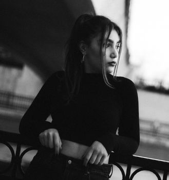 Stylish black and white portrait of a young woman posing confidently outdoors.