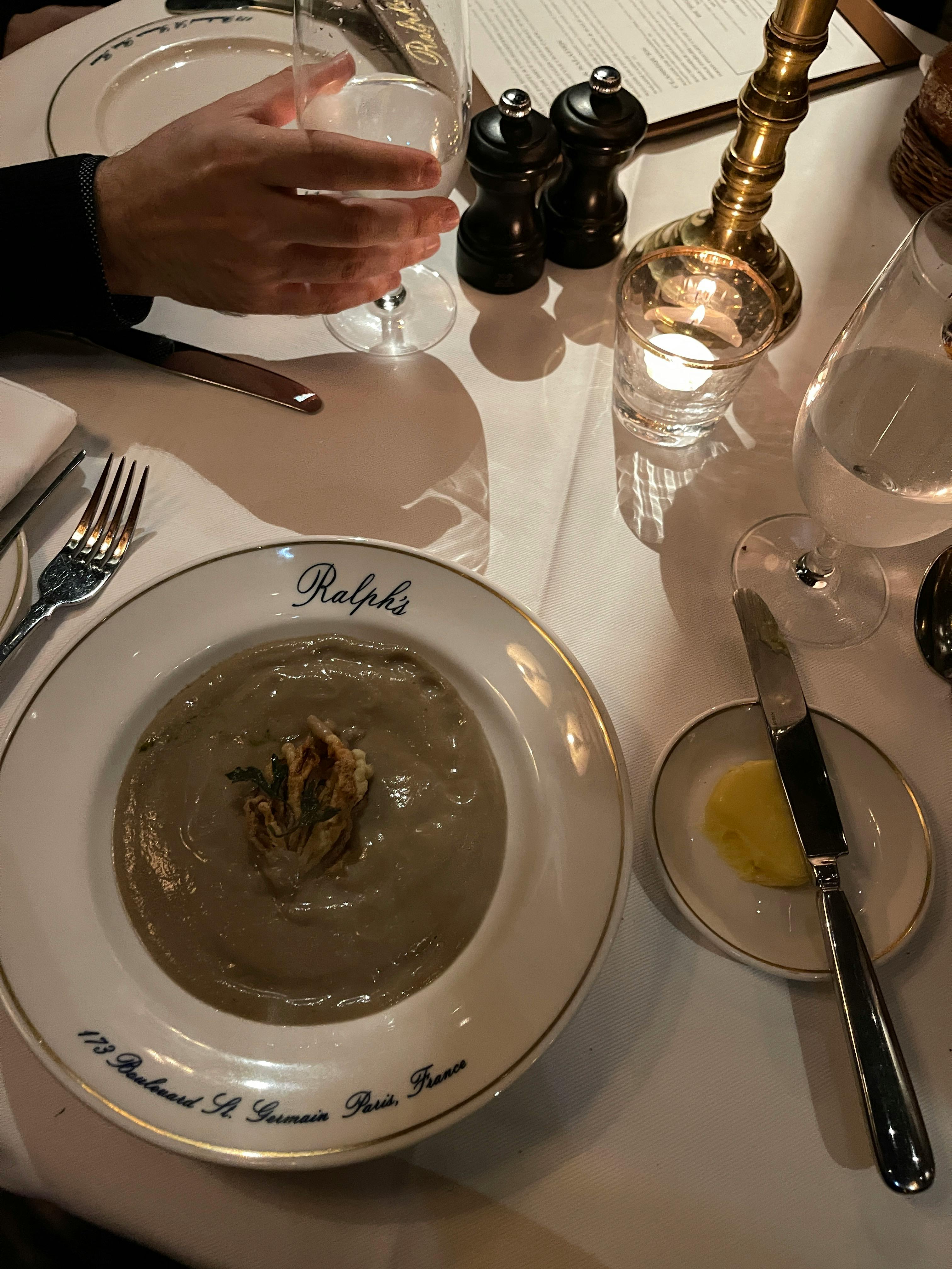 Sophisticated dining experience captured with a focus on a creamy soup dish at an elegant restaurant table.