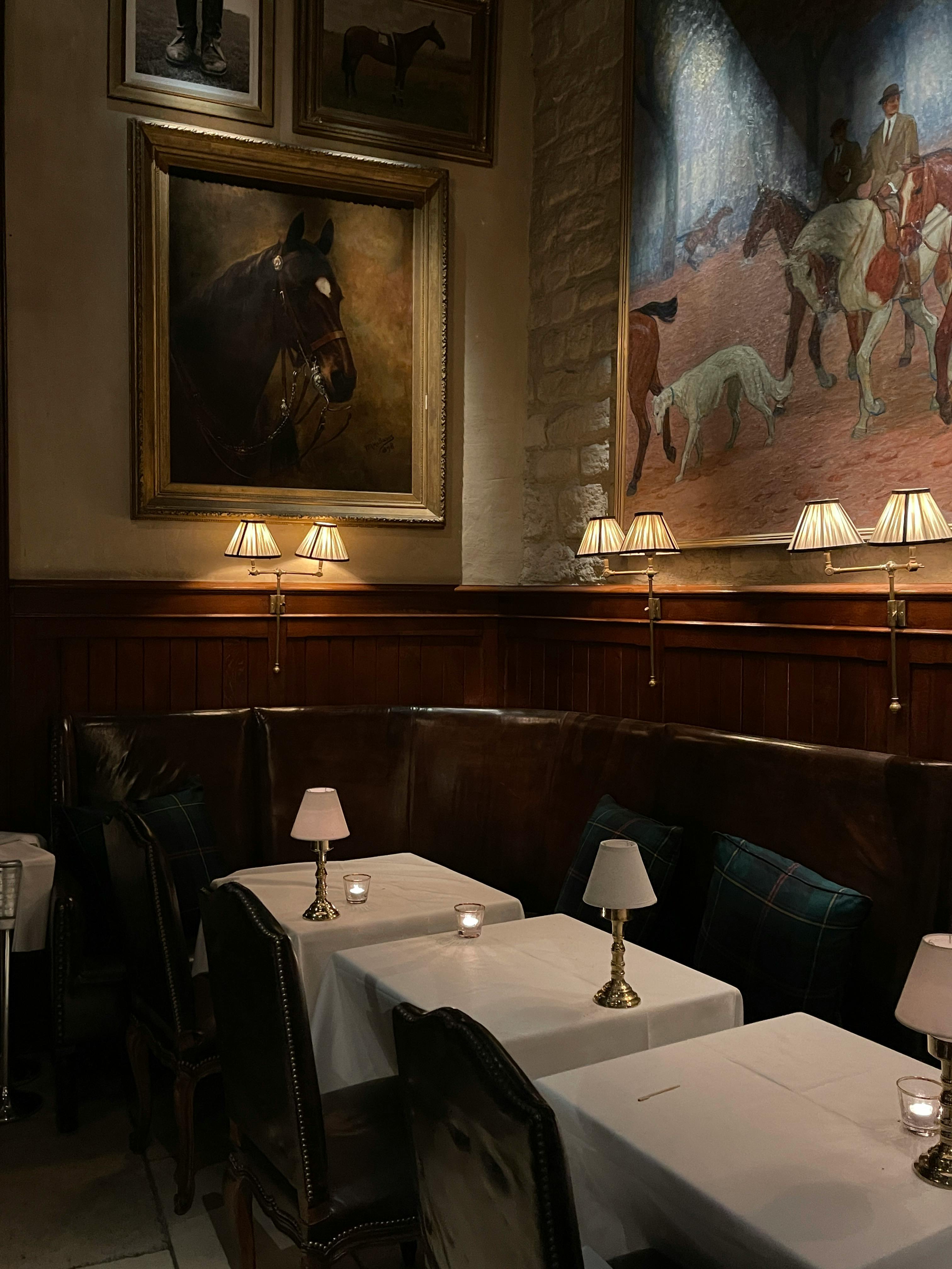 Elegant vintage restaurant setting with artistic horse paintings and soft lighting.